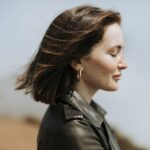 Side view of  a woman in leather jacket standing in a park